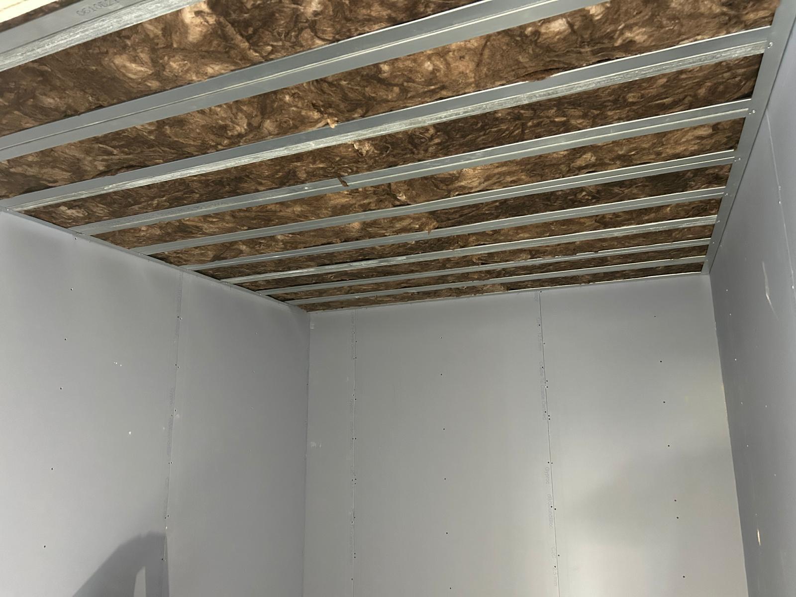 Verlaagd plafond in aanbouw met verzinkte stalen profielen en minerale wol tussen de regels